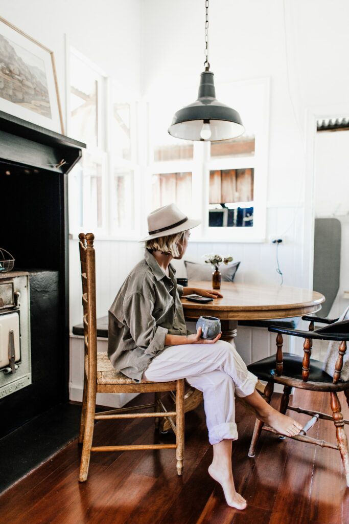 femme avec tenue d'intérieur ample assise à table avec une tasse